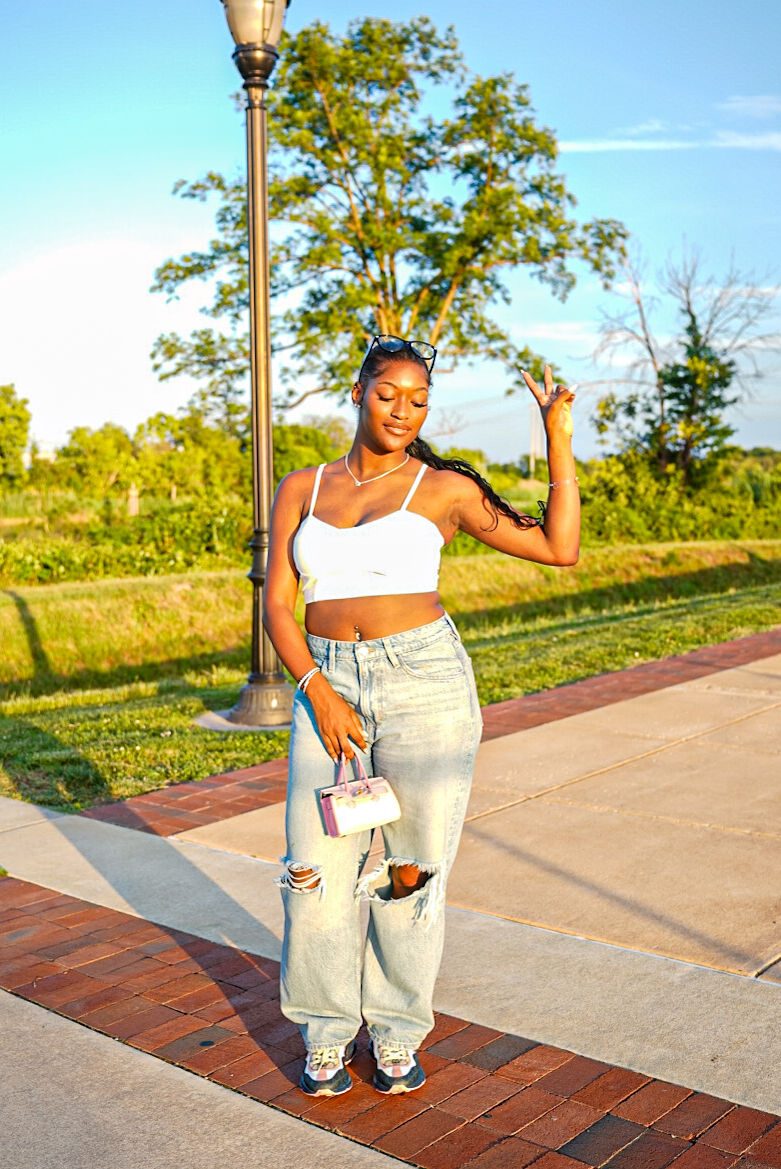 A woman posing by a lamppost on a sunny path