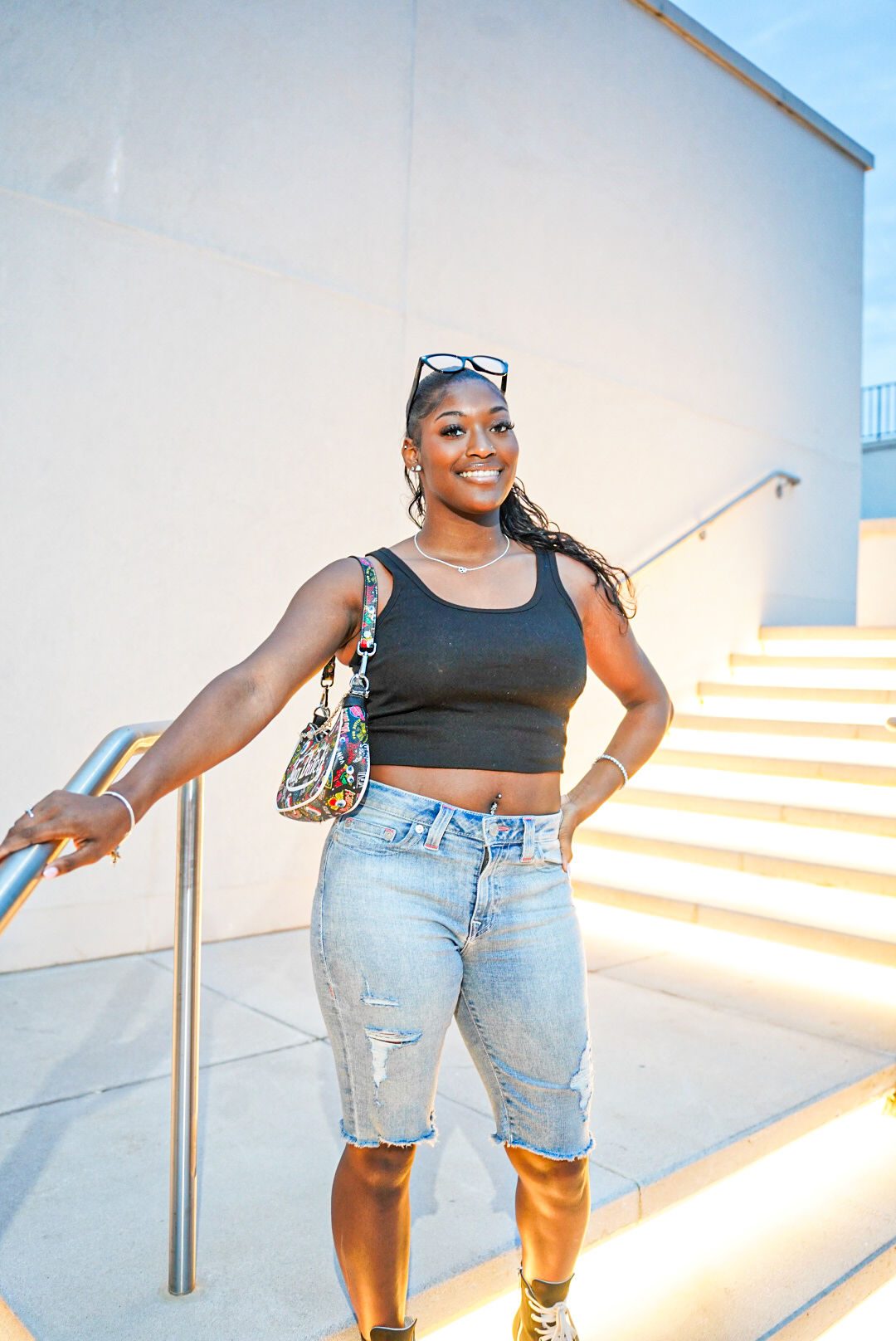 A woman posing on lit outdoor steps at sunset