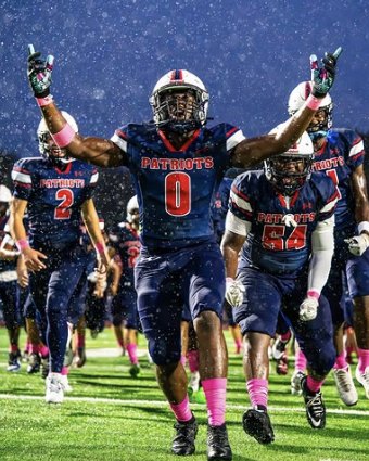 Football team celebrating on the field in the rain
